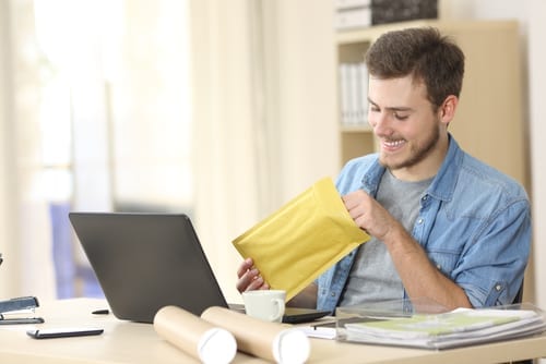 man smiling while opening direct mail