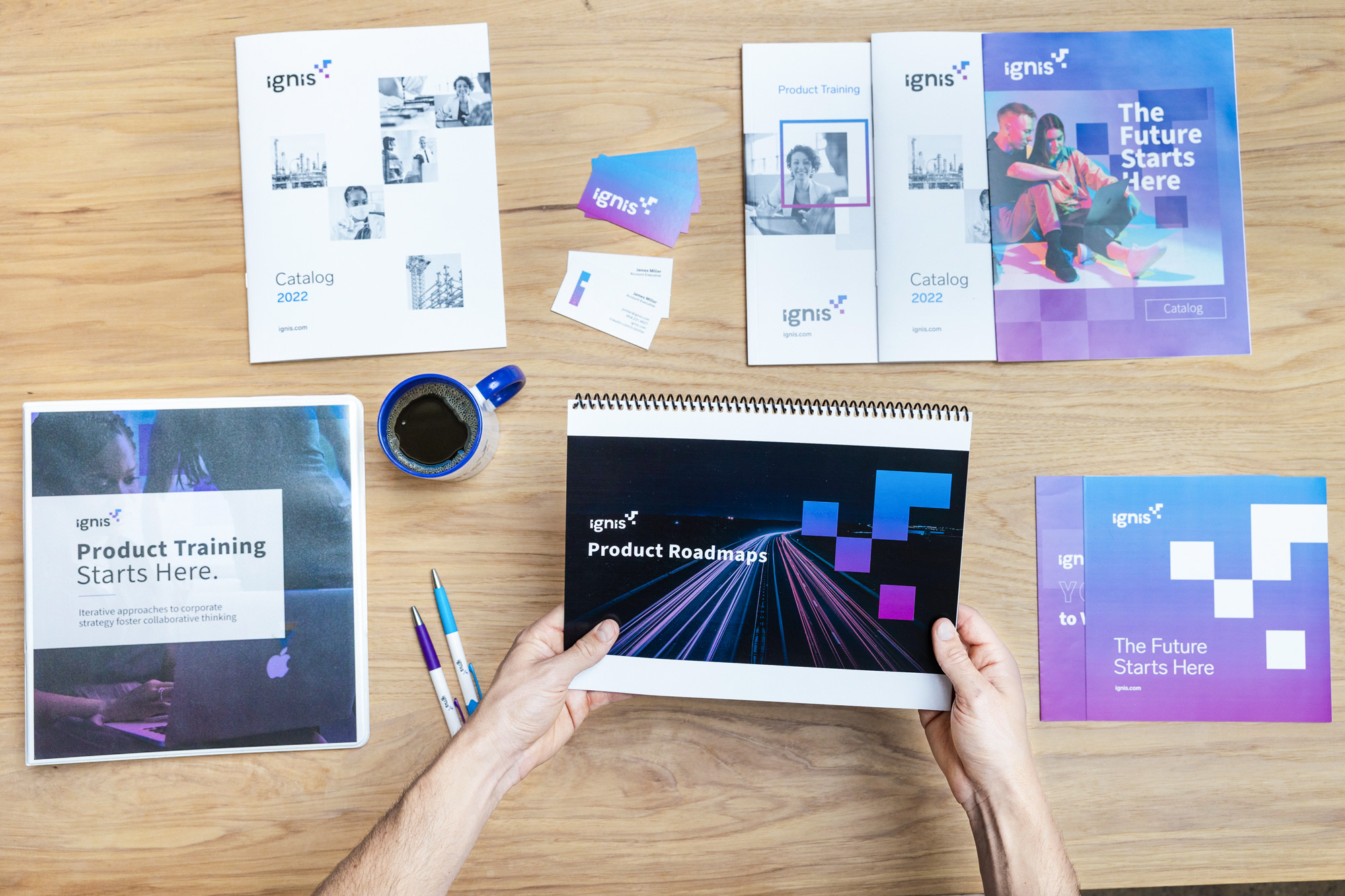 assorted printed products on desk, person holds printed presentation