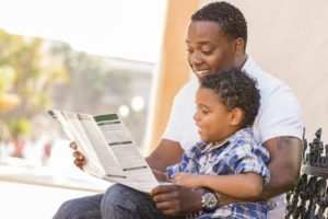 man and boy reading company brochure smiling