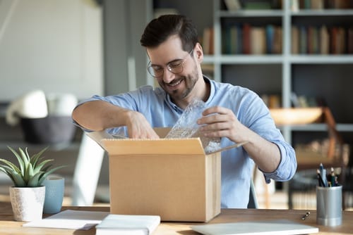smiling man opening package with SWAG