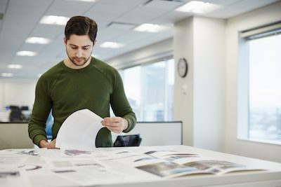 man in office checking proofs of files